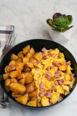 Çırpılmış yumurta ve konserve jambon yanında patates kızartması.