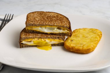 Kızarmış yumurta ve peynirli sandviç. Haşhaşla servis ediliyor.