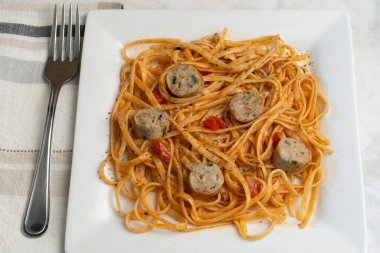 soslu spagetti ve tavuk ıspanaklı sosis ile servis edilen otlar.