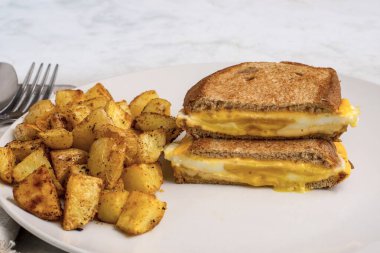 Kızarmış yumurta eritilmiş kahvaltı sandviçi ve patates kızartması.