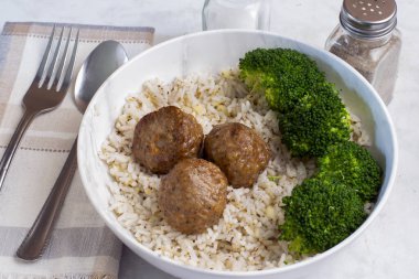 Brokoli ve pirinçle servis edilen üç İtalyan usulü köfte.