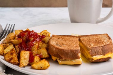 Kızarmış yumurta eritilmiş kahvaltı sandviçi ve patates kızartması.