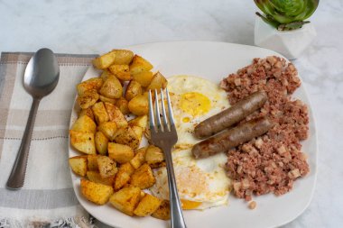 Kahvaltıda az pişmiş yumurta, mısır gevreği ve patates kızartması.