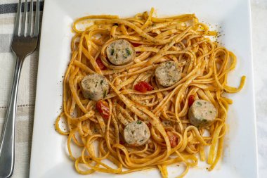 soslu spagetti ve tavuk ıspanaklı sosis ile servis edilen otlar.