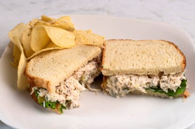 Patates cipsiyle servis edilen beyaz ekmeğin üzerine doğranmış turşulu tavuk salatası.