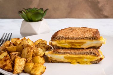 Kızarmış yumurta eritilmiş kahvaltı sandviçi ve patates kızartması.