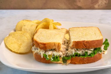 Patates cipsiyle servis edilen beyaz ekmeğin üzerine doğranmış turşulu tavuk salatası.