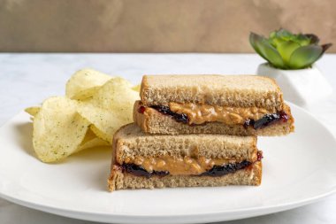 Patates cipsiyle servis edilen buğday ekmeğine fıstık ezmesi ve reçel.