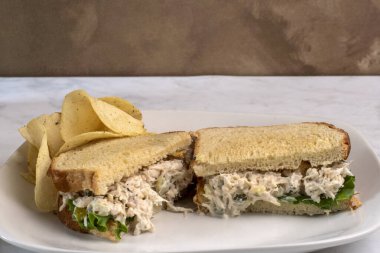 Patates cipsiyle servis edilen beyaz ekmeğin üzerine doğranmış turşulu tavuk salatası.