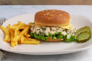 Tavuklu salata turşuyla karıştırılmış susamlı çörek ve yanında patates kızartması.