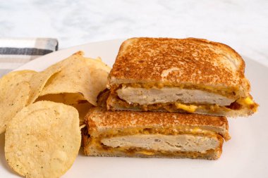 Patates cipsiyle servis edilen eritilmiş peynirli tavuk filetosu..