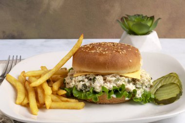 Tavuklu salata turşuyla karıştırılmış susamlı çörek ve yanında patates kızartması.