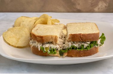 Patates cipsiyle servis edilen beyaz ekmeğin üzerine doğranmış turşulu tavuk salatası.