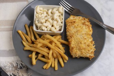 Fırında balık, patates kızartması ve makarna salatası.