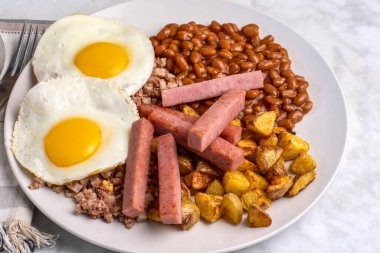 Kızarmış yumurta, sığır eti, fırında fasulye ve patates kızartmasıyla servis edilen patates kızartması.