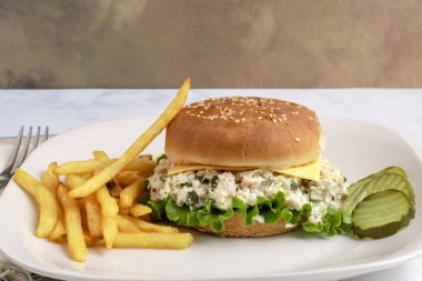 Tavuklu salata turşuyla karıştırılmış susamlı çörek ve yanında patates kızartması.