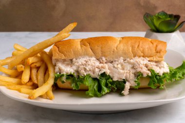 Soğanlı tavuk salatası ve patates kızartmasıyla servis edilen bir alt rulo marul.