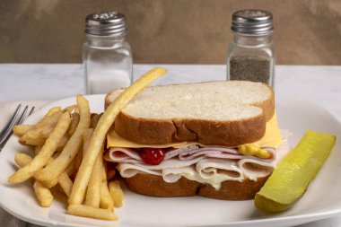 hindi jambonlu ve peynirli beyaz ekmekli patates kızartması ile servis ediliyor.