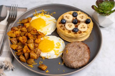  fried eggsand homefries top with cheese served with  waffles