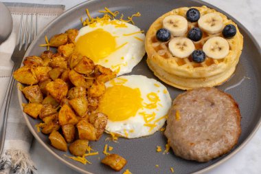  fried eggsand homefries top with cheese served with  waffles