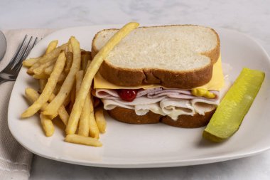 hindi jambonlu ve peynirli beyaz ekmekli patates kızartması ile servis ediliyor.