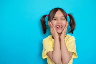 Komik ya da heyecanlı küçük bir kızın yakın plan portresi kayıp bebek dişi gülüşü mavi arka planda fotokopi aletiyle eğleniyor..