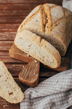 Freshly baked bread loaf on rustic wooden cutting board and napkin