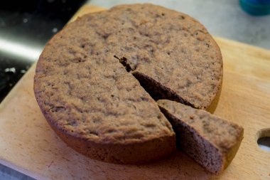 Dilimlenmiş yuvarlak pasta, dokulu bir iç mekan ortaya çıkarıyor. Tahta kesme tahtasına yerleştirilmiş. Kaba görünümlü, altın-kahverengi kabuklu, servis için mükemmel ya da daha fazla dekorasyon için.