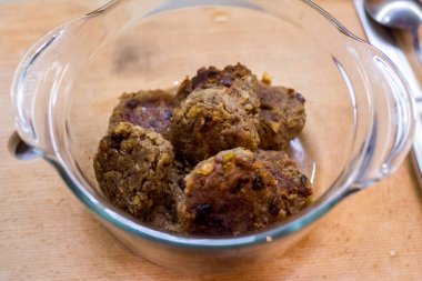 Açık renkli bir yüzeyde cam kabın içinde öğütülmüş etten yapılmış köfteler. Kahverengi, yuvarlak, basit. Ev yapımı, kırsal, besleyici, günlük yemek hazırlama.