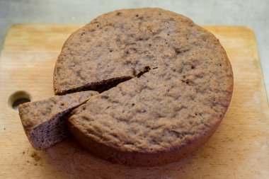 Dilimlenmiş yuvarlak pasta, dokulu bir iç mekan ortaya çıkarıyor. Tahta kesme tahtasına yerleştirilmiş. Kaba görünümlü, altın-kahverengi kabuklu, servis için mükemmel ya da daha fazla dekorasyon için.