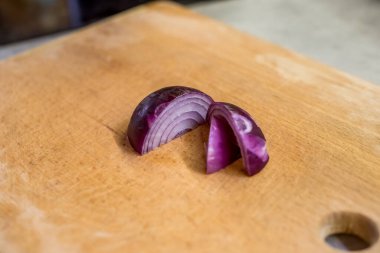 Dilimlenmiş soğan tahtanın üzerinde duruyor. Mor katmanlar yüzey dokusuyla tezat oluşturuyor. Yumuşak ışık yapıyı ön plana çıkarır. Arka plan bulanık, taze malzemeyi vurguluyorum. Basit bileşim odaklanmayı arttırır