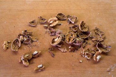 Mutfak kesme tahtasına serpiştirilmiş ceviz. Deniz kabuğu ve fındık parçaları eşit karışmamış. Modern ortamda sağlıklı gıda hazırlığı. Yemek pişirmek için basit temiz sahne.