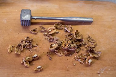 Mutfak tokmağıyla ahşap tahtaya saçılmış cevizler. Metal kafanın kare girintileri var. Düz olmayan parçalar. Basit bir hazırlık sahnesi. Yemek pişirme başlıyor..