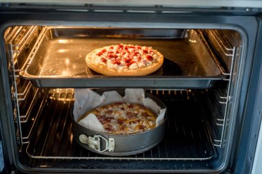 Ev yapımı pizza fırında peynirli, eritilmiş ve soslu. İçi aydınlandıkça altın kabuk oluşuyor. Kırsal yemek pişirme süreci yemeğin raflarda eşit derecede piştiğini gösteriyor. Lezzetli sonuçlar bizi bekliyor..