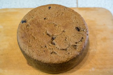 Tahtaya yerleştirilmiş büyük vişneli pasta, altın hamuru pişmiş dokuyu, küçük çatlakları, dağınık noktaları gösteriyor. Taze sünger nazikçe soğur, dilimlenmeye hazır, sıcak ev yapımı toplanma sırasında paylaşılır..