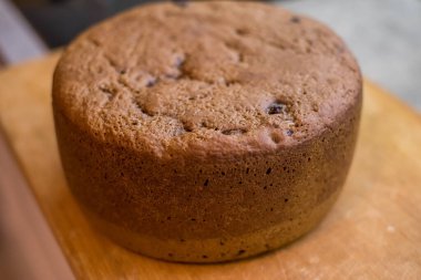 Tahtaya yerleştirilmiş büyük vişneli pasta, altın hamuru pişmiş dokuyu, küçük çatlakları, dağınık noktaları gösteriyor. Taze sünger nazikçe soğur, dilimlenmeye hazır, sıcak ev yapımı toplanma sırasında paylaşılır..