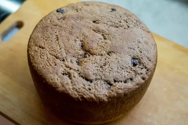 Tahtaya yerleştirilmiş büyük vişneli pasta, altın hamuru pişmiş dokuyu, küçük çatlakları, dağınık noktaları gösteriyor. Taze sünger nazikçe soğur, dilimlenmeye hazır, sıcak ev yapımı toplanma sırasında paylaşılır..