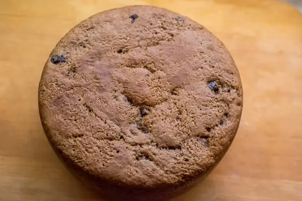 Tahtaya yerleştirilmiş büyük vişneli pasta, altın hamuru pişmiş dokuyu, küçük çatlakları, dağınık noktaları gösteriyor. Taze sünger nazikçe soğur, dilimlenmeye hazır, sıcak ev yapımı toplanma sırasında paylaşılır..