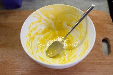 Kalın tabakta çırpılmış yumurta ve içine yerleştirilmiş kaşık var. Utensil mutfak sahnesindeki aşçılık sürecine dayanır.