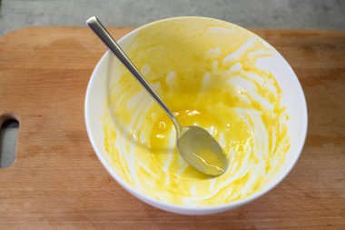 Kalın tabakta çırpılmış yumurta ve içine yerleştirilmiş kaşık var. Utensil mutfak sahnesindeki aşçılık sürecine dayanır.