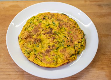 Omlet beyaz tabakta sunuldu. Tahta kesme tahtası bitişikte. Kahvaltı sona erdi; bileşenler daha önceki lezzetli yemeklerin birleşimi; servis seti tamamlandı. Sabah yemeği doğru değerlendirildi.!