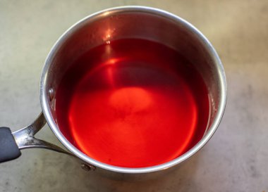 Paslanmaz çelik tencerede meyveli jöle hazırlığı. Sıvı karışımı tabana döküldü. İçindekiler ölçülü oranlarda birleştirildi.