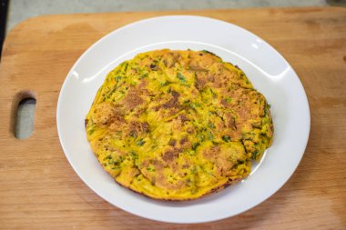 Omlet beyaz tabakta sunuldu. Tahta kesme tahtası bitişikte. Kahvaltı sona erdi; bileşenler daha önceki lezzetli yemeklerin birleşimi; servis seti tamamlandı. Sabah yemeği doğru değerlendirildi.!