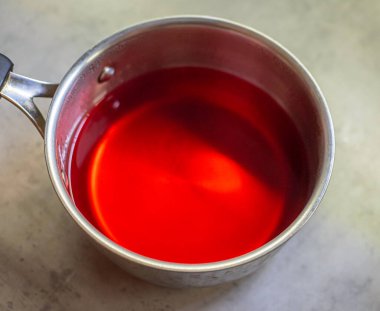 Paslanmaz çelik tencerede meyveli jöle hazırlığı. Sıvı karışımı tabana döküldü. İçindekiler ölçülü oranlarda birleştirildi.