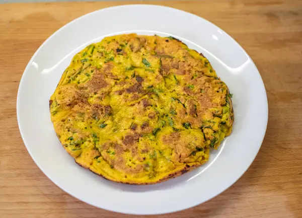 Omlet beyaz tabakta sunuldu. Tahta kesme tahtası bitişikte. Kahvaltı sona erdi; bileşenler daha önceki lezzetli yemeklerin birleşimi; servis seti tamamlandı. Sabah yemeği doğru değerlendirildi.!