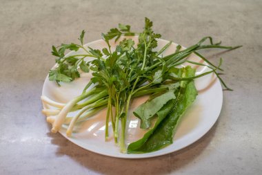 Tabakta ıspanak, maydanoz ve yeşil soğan var. Bileşenler aynı hizaya geldi. Sunum teknik kalır; gruplaşma ayrılık vurgusu yaratır. Yapılandırma, titizlikle sıralanmış çeşitli bölümlerden oluşur.