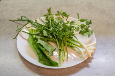 Tabakta ıspanak, maydanoz ve yeşil soğan var. Bileşenler aynı hizaya geldi. Sunum teknik kalır; gruplaşma ayrılık vurgusu yaratır. Yapılandırma, titizlikle sıralanmış çeşitli bölümlerden oluşur.