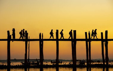 Amarapura, Myanmar - 22 Kasım 2016: Myanmar 'da gün batımında kimliği belirsiz kişiler U Bein köprüsünde yürüyor. U Bein köprüsü dünyanın en uzun meşe köprüsü..