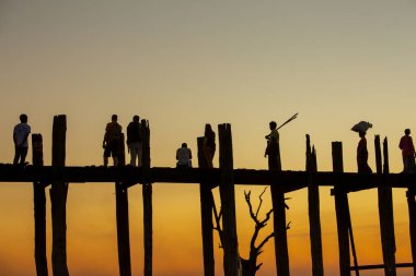 Amarapura, Myanmar - 22 Kasım 2016: Myanmar 'da gün batımında kimliği belirsiz kişiler U Bein köprüsünde yürüyor. U Bein köprüsü dünyanın en uzun meşe köprüsü..