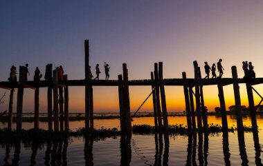 Amarapura, Myanmar - 22 Kasım 2016: Myanmar 'da gün batımında kimliği belirsiz kişiler U Bein köprüsünde yürüyor. U Bein köprüsü dünyanın en uzun meşe köprüsü..